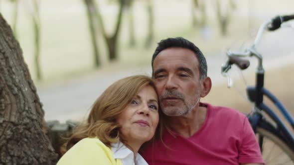 Senior Lovers Sitting on Bench Hugging and Dreaming