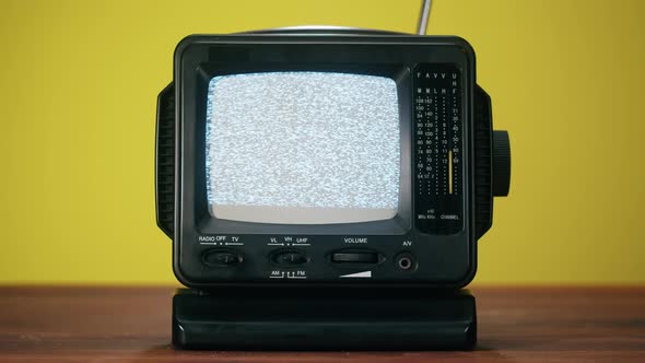 Small Old Television with Grey Interference Screen on Yellow Background