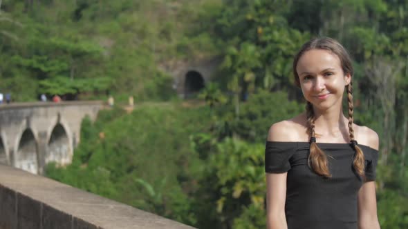 Pretty Girl Sits on Nine-arch Bridge Among Green Nature