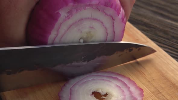 Closeup of a Knife Cut the Purple Onion Into the Rings on the Wooden Board