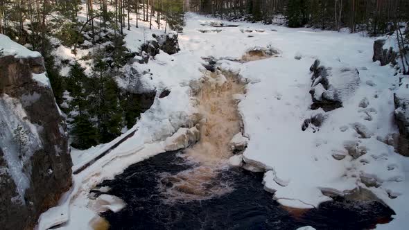 Aerial view of a waterfall in a Swedish forest during Winter