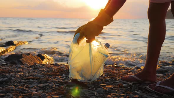 Hand Woman in Yellow Gloves Picking Up Empty Plastic Bottles Cleaning on the Beach