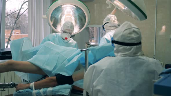 Surgeons in Safety Suits are Operating a Patient