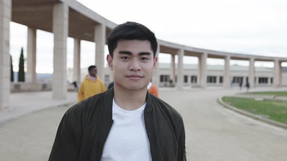 Front View of Young Asian Man Looking at Camera While Walking Outdoors