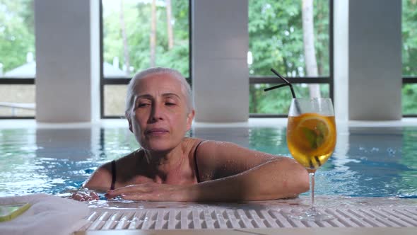 Mature Woman Swimming To Pool Side in Spa Hotel