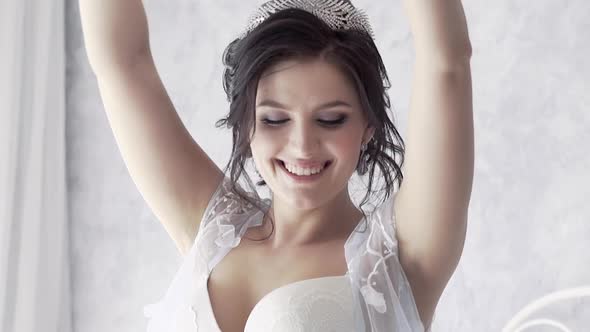 Young Smiling Brunette Bride in Lacy Wraper Tosses Pillow