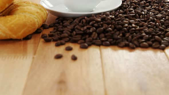 Coffee with roasted coffee beans and croissant