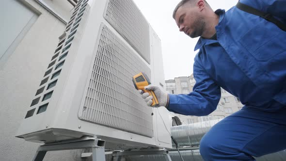 Technician uses a thermal imaging infrared thermometer to check the condensing