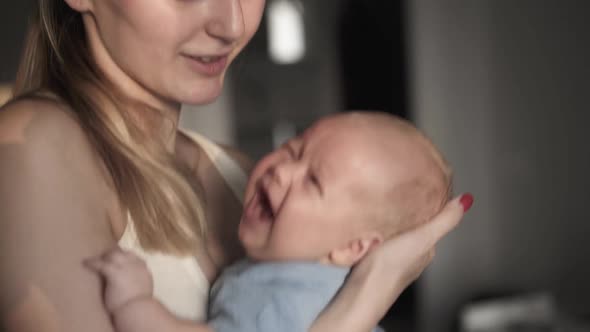 Happy Mother Hugging Newborn Baby and Amusing with Love