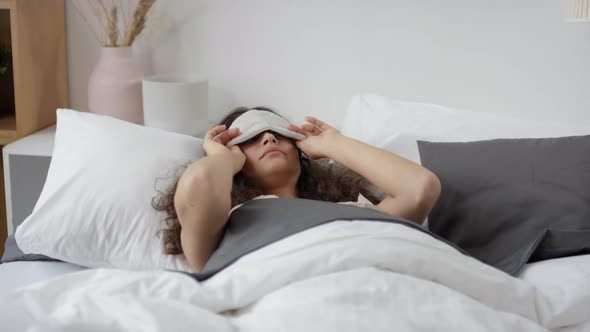 Young Woman Waking Up in Bed and Taking Off Sleep Mask