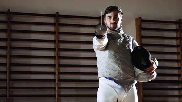 Man Walking in Fencing Gear and Holding Mask and Foil Before Duel