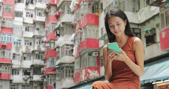 Woman using mobile phone in residential building in Hong Kong city