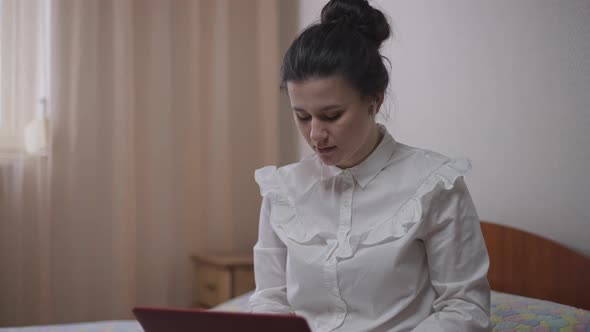 Young Busy Woman Surfing Internet on Laptop Talking Sitting Indoors at Home