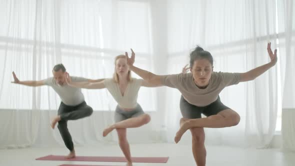 Yoga Class Group of Three Women and Man Exercising Healthy Lifestyle in In Bright Studio