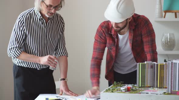 Professional Architect and Young Student Builder in Office.