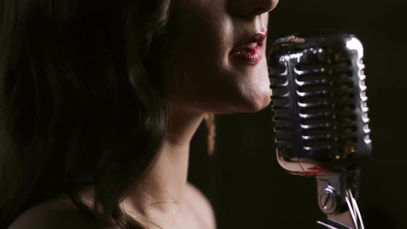 Woman Singer Singing on Microphone on Black Background, Closeup Lips Side View.