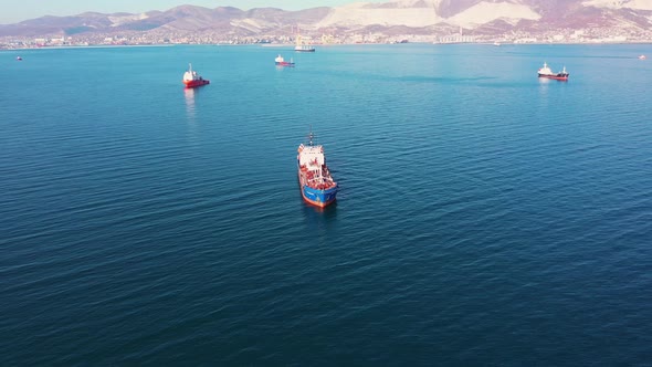 Aerial View Following the Ultra Large Cargo Ship at Sea Leaves Port at Sunset