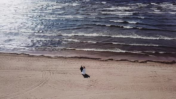 Bride and Groom Walk Beach Holding Hands