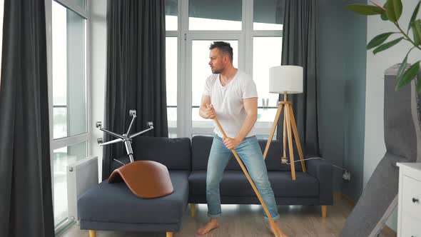 Man Cleaning the House and Having Fun Dancing and Singing with a Broom