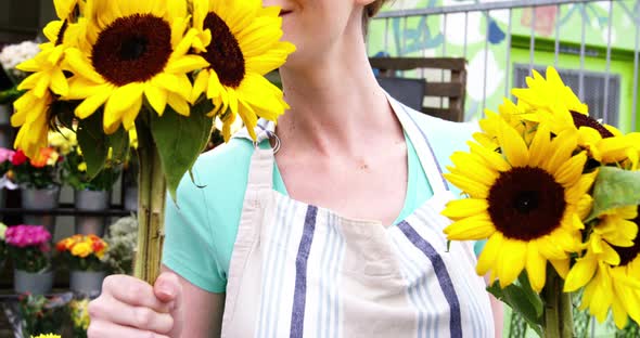 Beautiful female florist smelling bunch of sunflower