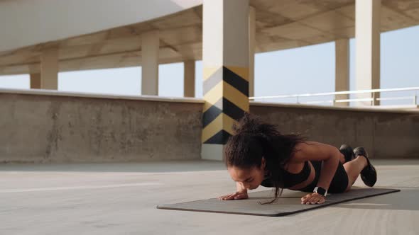 A muscular american woman doing push-ups on a yoga mat