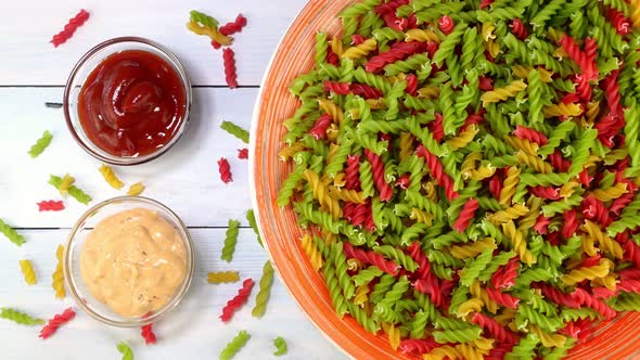 Multicolored Uncooked Raw Italian Fusilli Pasta Rotating Slowly on Turntable in Dish