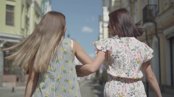 Back View of Two Walking Women with Shopping Bags