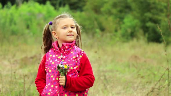 A portrait of a cute little girl. Beautiful Little girl enjoys the smell of flowers in the meadow