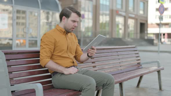 Upset Young Man Reacting to Loss on Tablet Outdoor