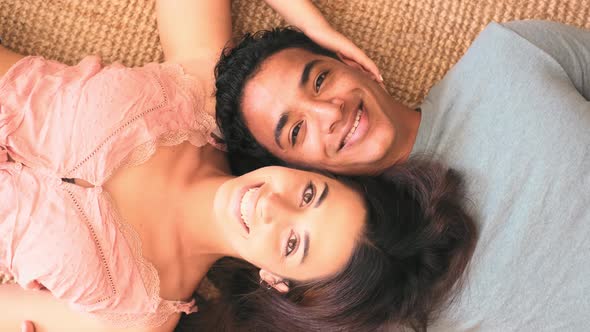 Happy young interracial couple viewed from above laying on the floor at home - cheerful