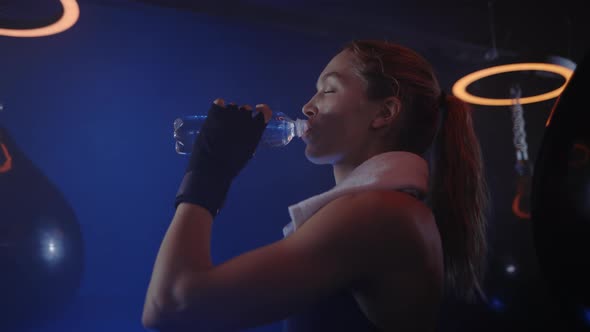 Woman Boxer is Drinking Water After the Training Feeling Thirsty and Carrying the White Towel on Her