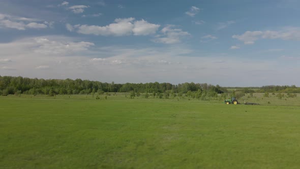 Tractor plows the ground on a green field