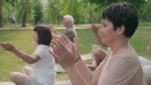 Woman Doing Yoga with Elderly People in Park