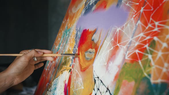 Hand of Unknown Female Painter is Drawing a Portrait on Canvas Creating Multicolored Picture in