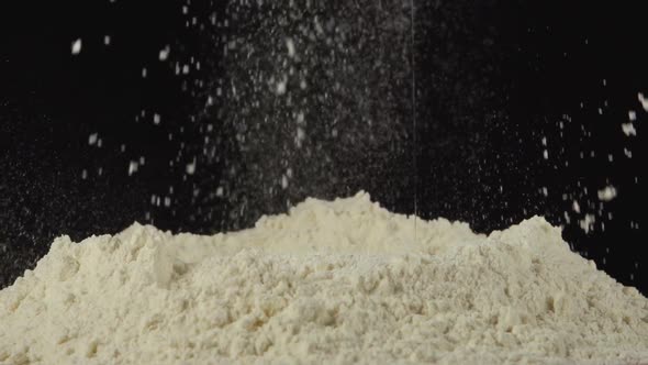 Splash - Egg Falls On A Pile Of Flour On A Black Background