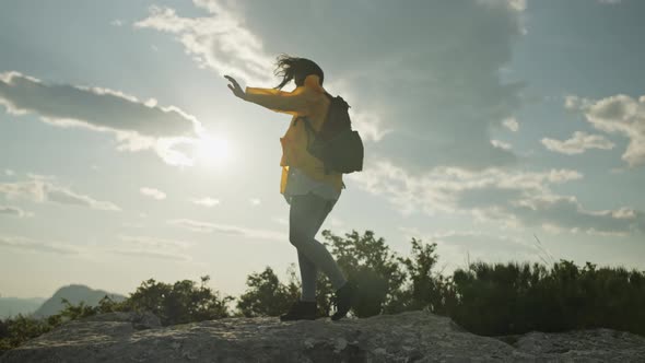 The Girl is Hiking Along the Rocks of the Mountain Range