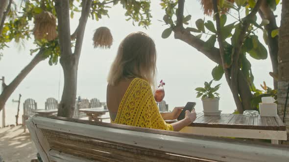 A Pretty Young Woman with Vitiligo Pigmentation Sits By the Beach Chatting on the Phone