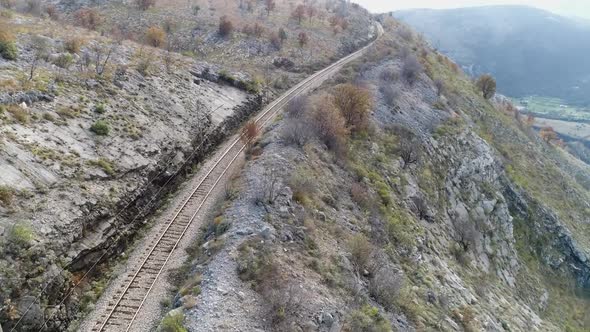 Aerial shot - Railway high up in the Montenegro mountains. Sunny, bright day with blue sky and cloud