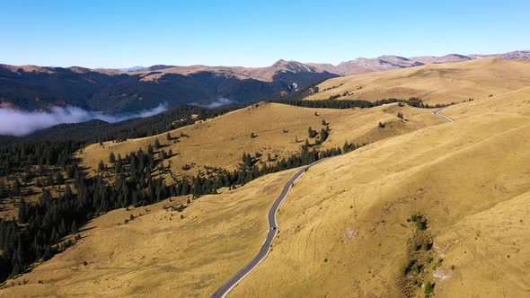 Aerial view of car driving down country road through rural rolling hills and mountain