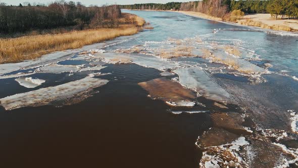 Low Flight Melting Snow and Ice at River Joining Sea in Spring Aerial