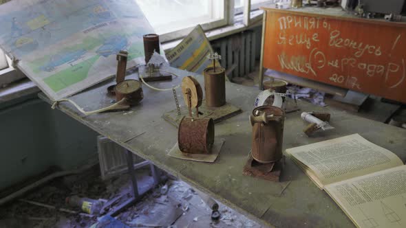 Rusty Cans And Open Book On Top Of The Dusty Table Inside The Classroom Of Abandoned School In Chern