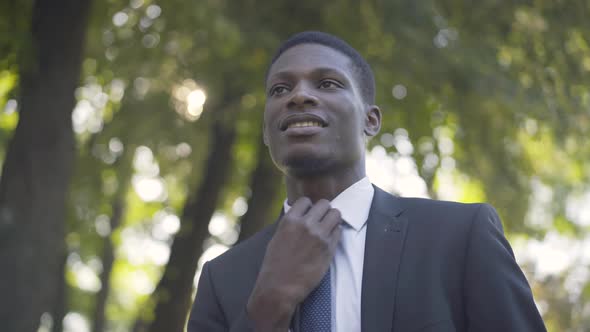 Bottom View of Young African American Man Loosening Necktie and Sighing. Portrait of Handsome