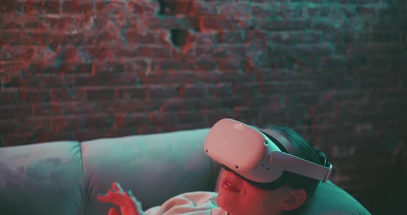 Camera moves to young woman laying on a couch wearing vr goggles