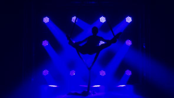 Female Aerial Gymnast Performing Rotate and Twine on a Red Silk. Exciting Acrobatic Show. Dark Smoky