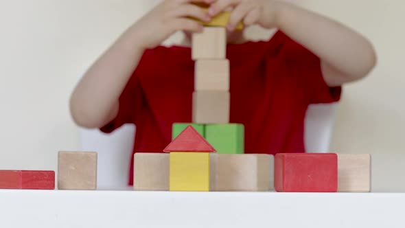 little kid playing at table with eco wooden colorful cubes,building a tower.house shape from cubes
