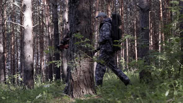 Two Hunter Men in Camouflage Clothes with Guns Walking Through Forest During Hunting Season. Man