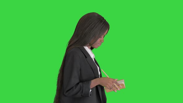 Pretty Young Black Woman Writing in Notepad on a Green Screen, Chroma Key