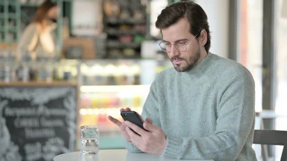 Young Man Using Smartphone Cafe