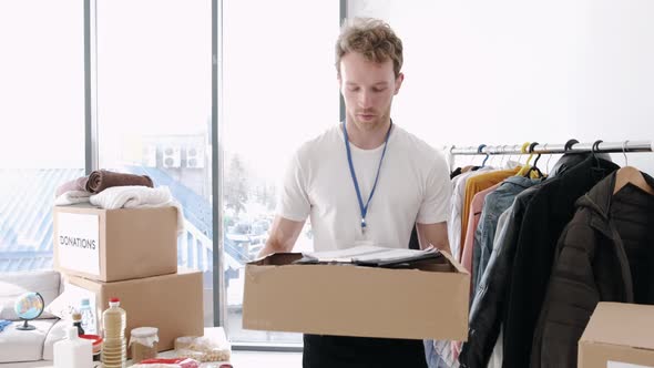 Young Volunteer Checking Clothes Donation Box and Making Notes Humanitarian Aid