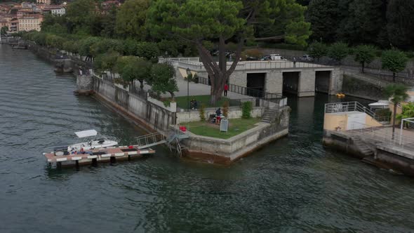 Drone pulling back from people at pier at Lake Como, Italy